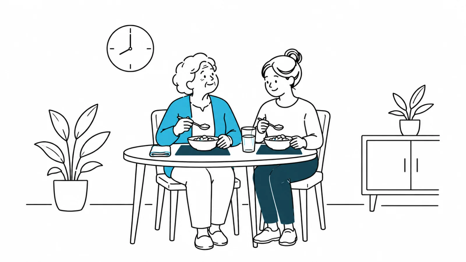 Uma mulher idosa e a sua cuidadora, sentadas à mesa, tomam a refeição com individuais de cor contrastante debaixo dos pratos. O relógio marca as oito horas.